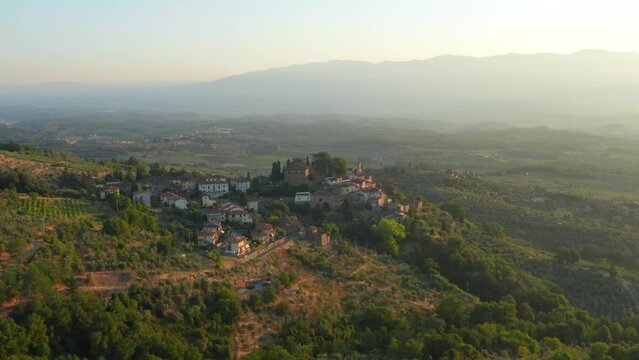 Famous Tuscany village on hill ridge at sunset. Flying over town open valley