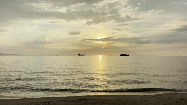 Scenic view of ships sailing in a sea crashing against the beach at sunset