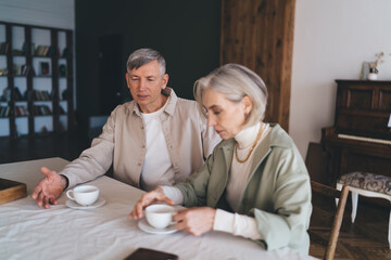 Mature couple talking while having coffee at home