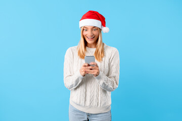 Excited woman with phone in Santa hat