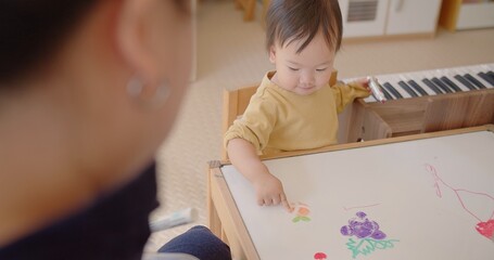 Happy family activity adorable Asian toddler child daughter girl painting fruits on whiteboard...