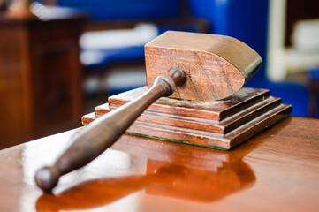 Wooden hammer sits on a table in a Craft Lodge room in a Masonic hall.