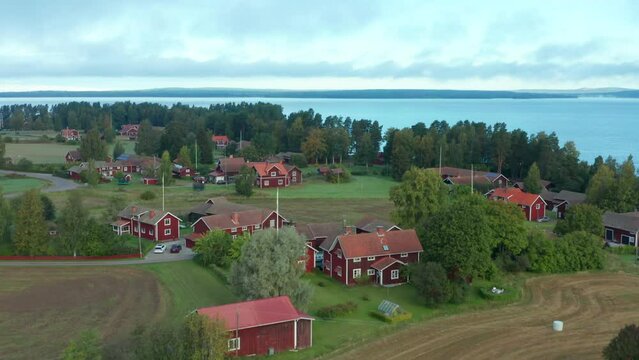Drone flying over Swedish homes. village by a lake with red summer cabins