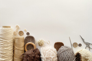 Top view of knitting accessories: balls of wool yarn, crochet hook, scissors, buttons.