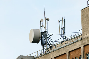 Microwave antenna on top of a telephone exchange beside cellular network antennas.