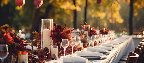 Fototapeta na wymiar Autumn themed outdoor wedding with long white clothed banquet tables adorned with floral arrangements candles and tableware Copy space image Place for adding text or design