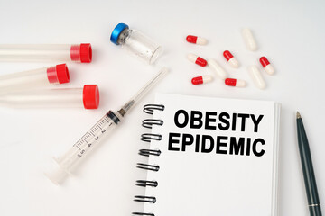 On the table are pills, injections, a syringe and a notepad with the inscription - obesity epidemic