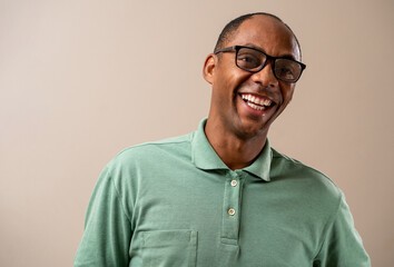 Man wearing glasses smiling on pastel background.