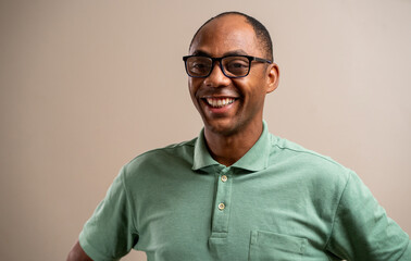 Black man wearing glasses smiling on pastel background.