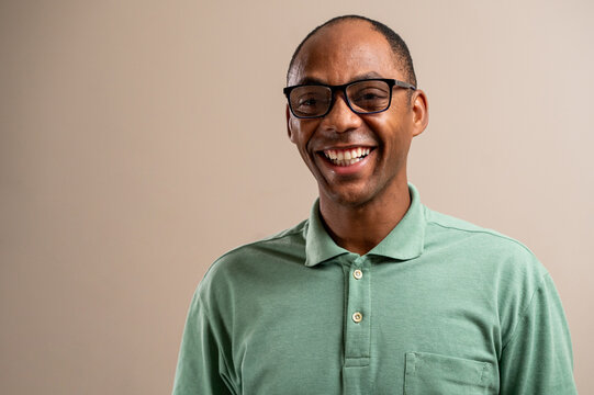 Man wearing glasses smiling on pastel background.