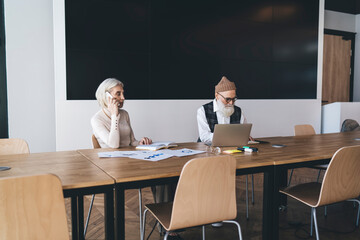 Serious senior woman talking on smartphone during work