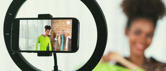 Woman influencer shoot live streaming vlog video review clothes crucial social media or blog. Happy young girl with apparel studio lighting for marketing recording session broadcasting online.