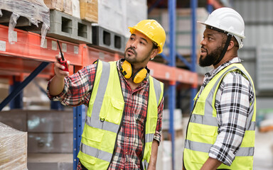 Asian, African diverse professional male workers inspecting, checking shipping stocks in storage, warehouse or factory for delivery, wearing safety hat. Commercial Industry Business Concept.
