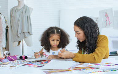 Beautiful adult mother teaching, bonding her mixed race African little cute daughter girl using...