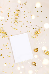 Festive gold background. Empty paper blank, shining stars confetti and fairy lights on beige and Set Sail Shampagne background. Christmas. Wedding. Birthday. Flat lay, top view, copy space