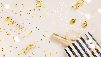 Festive gold background. Shining stars confetti, party streamers and decoration, holiday package on beige paper table. Christmas. Wedding. Birthday. Flat lay, top view, copy space.