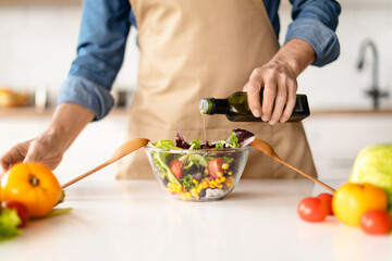 Healthy Nutrition Concept. Man Seasoning Vegetable Salad While Cooking In Kitchen