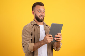 Shocked funny european millennial man with beard look at tablet, using app for social networks