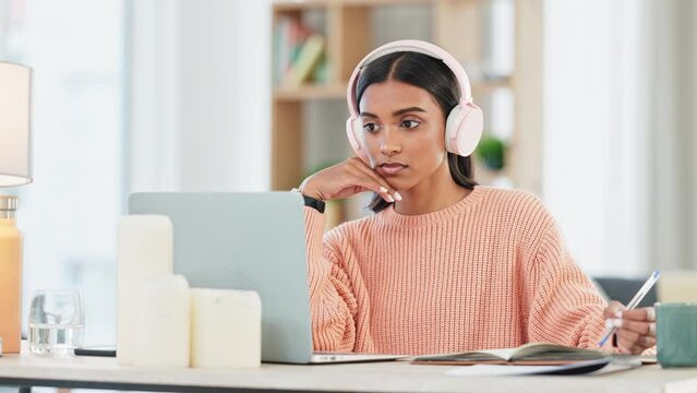 Student listening to online lesson, researching on laptop and listening to music in home living room. Woman wearing headphones for calming meditation song or binaural beats to help concentrate