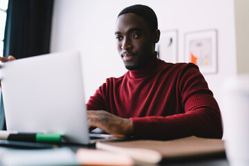 Calm black man surfing netbook in office