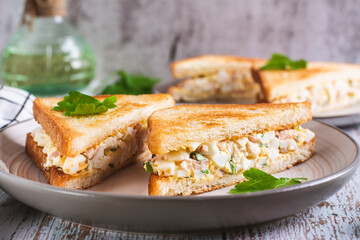 Chopped sandwiches with egg, bacon and herbs salad on a plate on the table