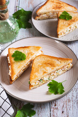 Bacon, egg and herb salad in a trendy chopped grilled sandwich on a plate vertical view
