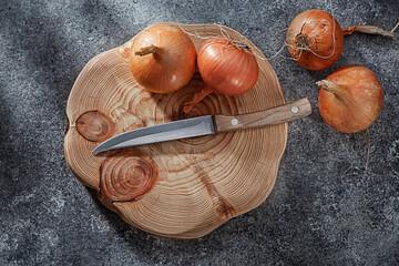 Wooden Cutting Board With Onion And Kitchen Knife.