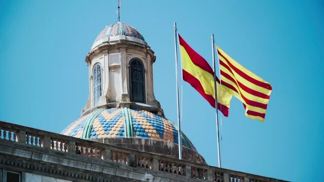 Spanish and Catalan flags waving atop the Palau de la Generalitat de Catalunya palace in Barcelona