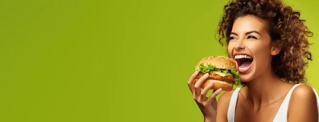 Tuinposter portrait of woman eating delicious cheeseburger on color background, generative ai © AIGen