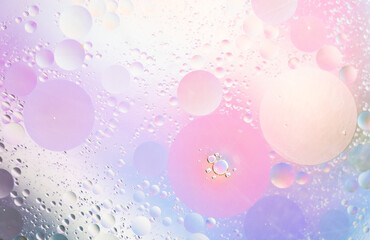 Abstract background in lilac and pink soft tones. Macro drops of oil on surface of the water. Delicate cosmetic background for advertising products. 