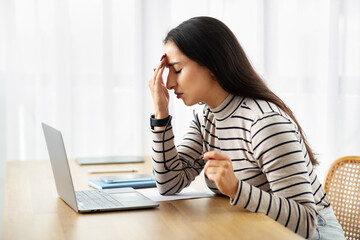Sad young arab woman work at computer, suffer from migraine, health problems, pain and headache
