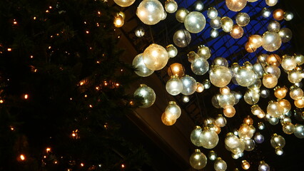 Festivité de Noel, ambiance de fête, entrée d'un grand magasin de produits parisien, installation de sapin avec guirlandes et sol rempli de grosses jolies ampoules, décoration lumineuse originale,  - obrazy, fototapety, plakaty