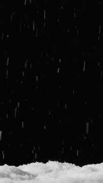 Vertical video. Snow background. Winter night. Blur white flakes falling on pile isolated on black defocused ice particles on dark sky.