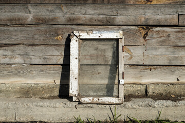 The white frame stands on the parapet, against the background of old boards.