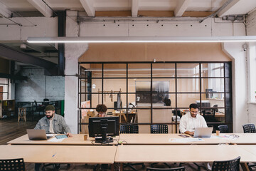 Group of coworkers working with laptops and computer in modern office