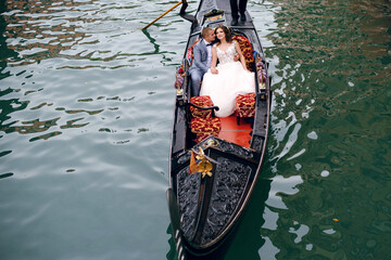 Gorgeous Wedding couple swimming on the gondola in Venice, Italy and enjoying of the beautiful old architecture - obrazy, fototapety, plakaty