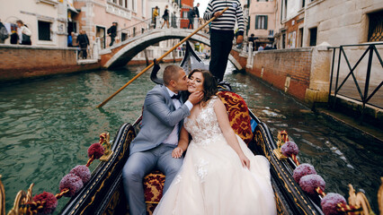 Gorgeous Wedding couple swimming on the gondola in Venice, Italy and enjoying of the beautiful old architecture © WellStock