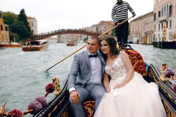 Gorgeous Wedding couple swimming on the gondola in Venice, Italy and enjoying of the beautiful old...