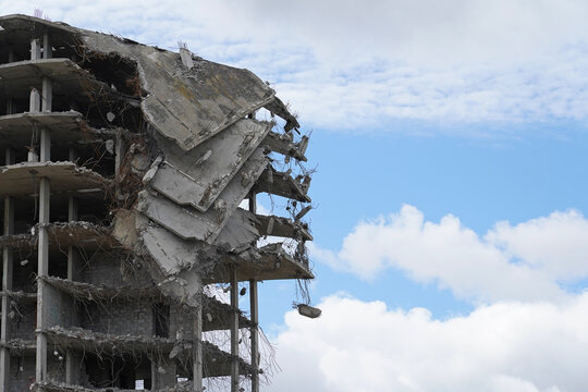 Industrial demolition of a multi-storey building, a building with collapsed floors against a blue sky with clouds