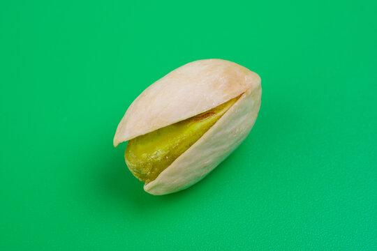 pistacho abierto con el fruto sin piel sobre fondo verde