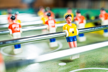 Scattered focus shot of table football game with red and yellow players and green plastic field,...