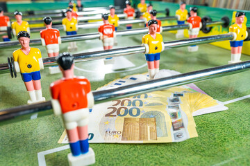 Table football game with euro bills scattered around plastic players, concept of manipulated paid...