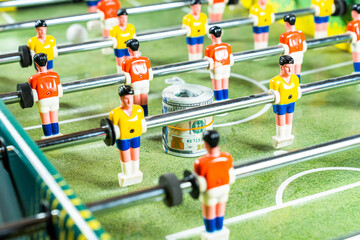 Table football game with rolled up dollar bills in the midst of plastic players, concept of betting and victory