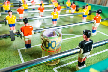 Table football game with rolled up euro bank notes in front of plastic goal keeper, concept of...