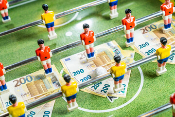 Table football game with euro bills scattered under figures of the players, concept of betting and...
