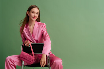 Fashionable beautiful happy smiling woman wearing trendy pink satin suit blazer, trousers, holding...