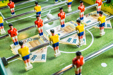 Beautiful shot of table football with 200 euro bills scattered on the plastic field, concept of gambling industry