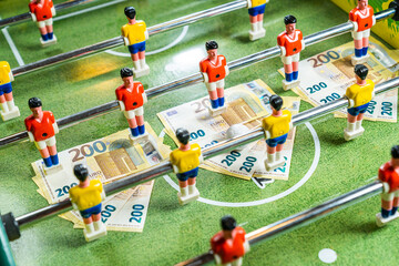Table football game with euro bills placed under yellow and red plastic players, concept of...