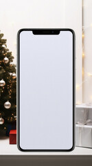 Smartphone with blank white screen on shelf in front of christmas tree.