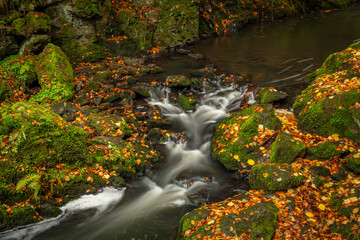 Fototapeta na wymiar Doubrava river with color rock with moss in autumn day near Bilek village